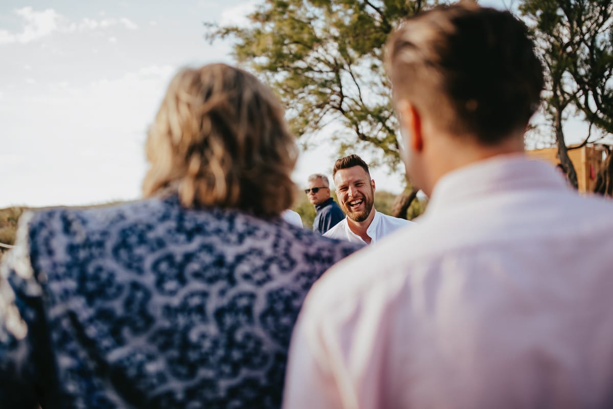 A wedding guest laughs at the groom with all his heart.