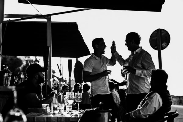 The brother of the groom and a guest give a hearty laugh high five.