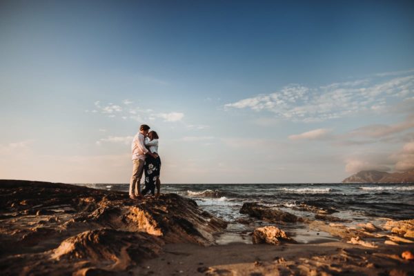 The bride and groom kiss lovingly at the sea.