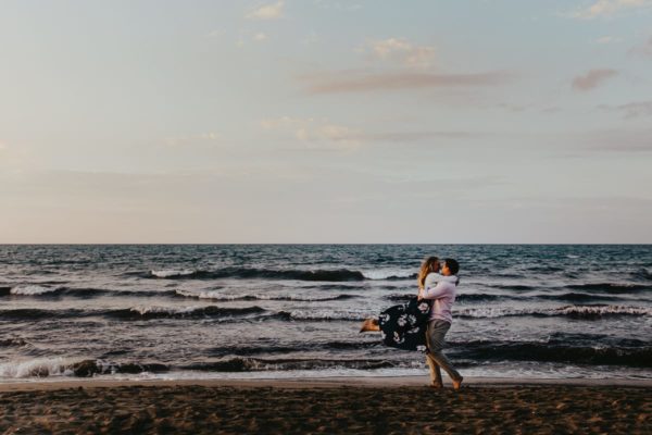 We see an overjoyed newlyweds in front of the sea. He lifts her up and turns.