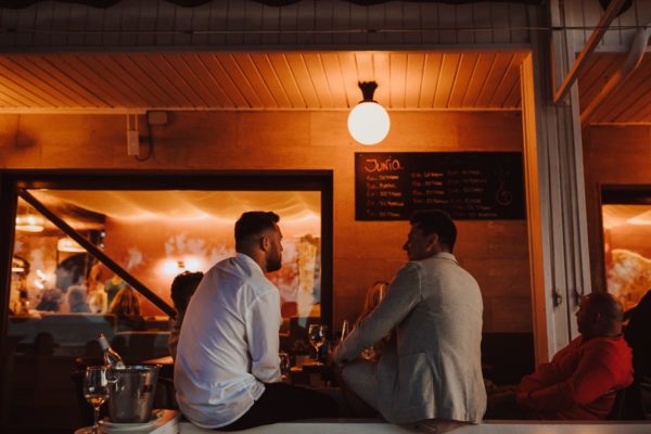 Two guests sitting on the parapet of the veranda of the bar and talk by warm lantern light.