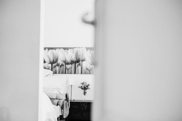 Creative view of the groom's feet. He is lying in the bed. The photo is in black and white.