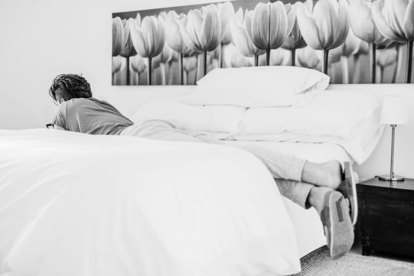 The groom is lying on the bed and is busy with his smartphone.