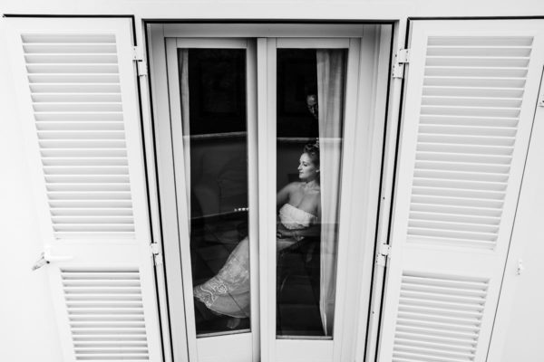 The bride photographed while styling from the outside through the window of the finca.