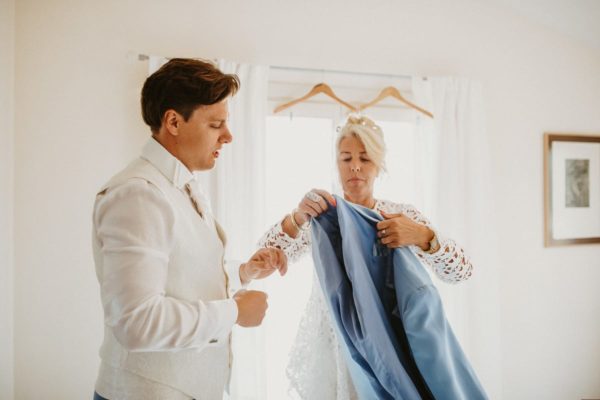 The mother helps her son while putting on the jacket.