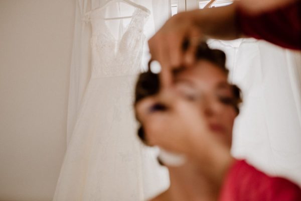 Snapshot during make-up with the focused wedding dress in the background and the blurred bride in the foreground.