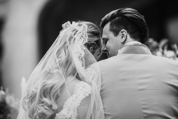 View from behind of the newlyweds, who are nestling together while they are listening to the singer named Angel.