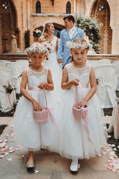 Bride and groom on their way out of the church. In front of them are the little flower girls scattering rose petals.