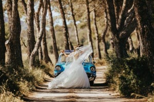 The newlyweds dance in front of the vintage car in nature.