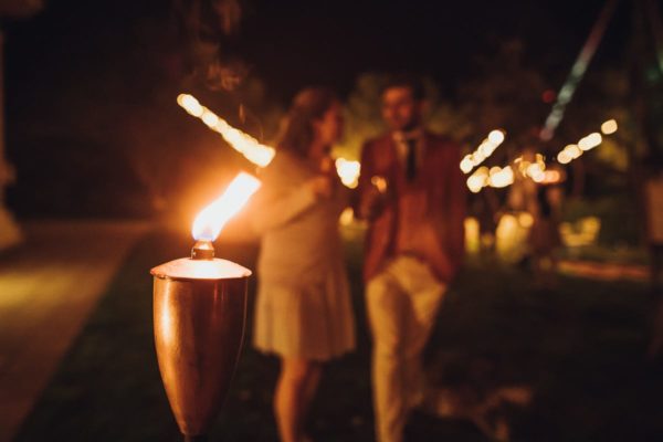 A focused burning torch in the foreground. and a couple out of focus on their way to the disco party.