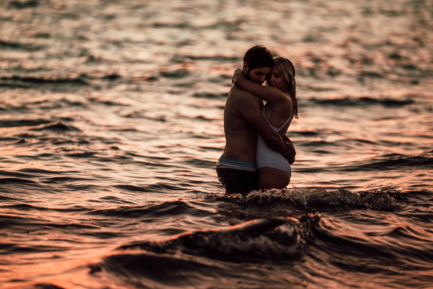 Intimate embrace of a beautiful young couple standing in water on the beach in Majorca.