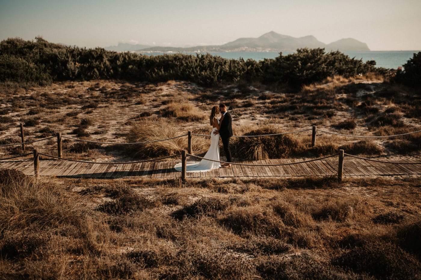 Bridal couple in the middle of the dunes closed to the beach in Alcudia